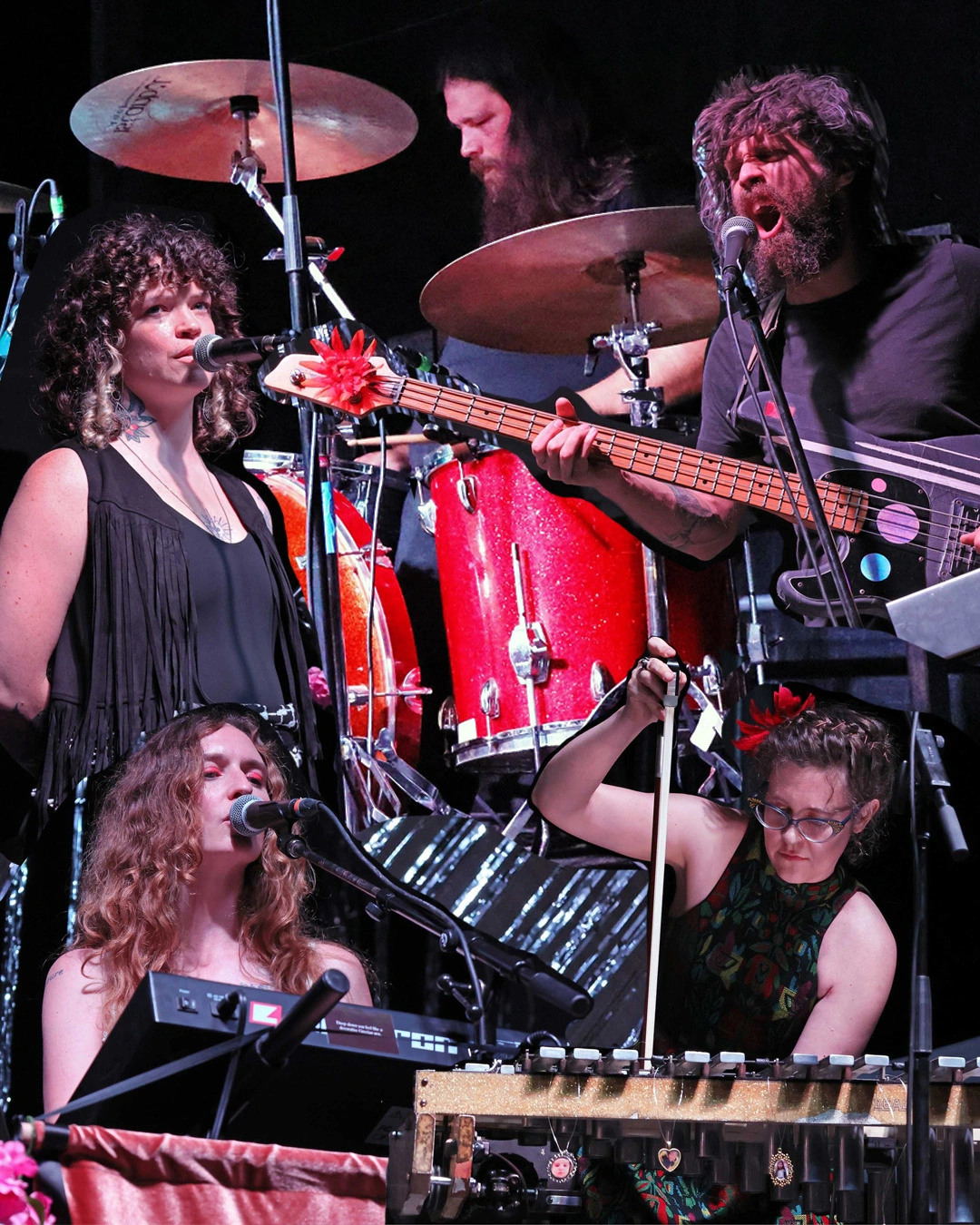 a collage of a band of people playing music. There's a lot of red here. Red drums, red lips. And a lot of movement, and open mouths that appear to be singing.