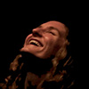 someone leaning her head back laughing with light on her face in a dark room