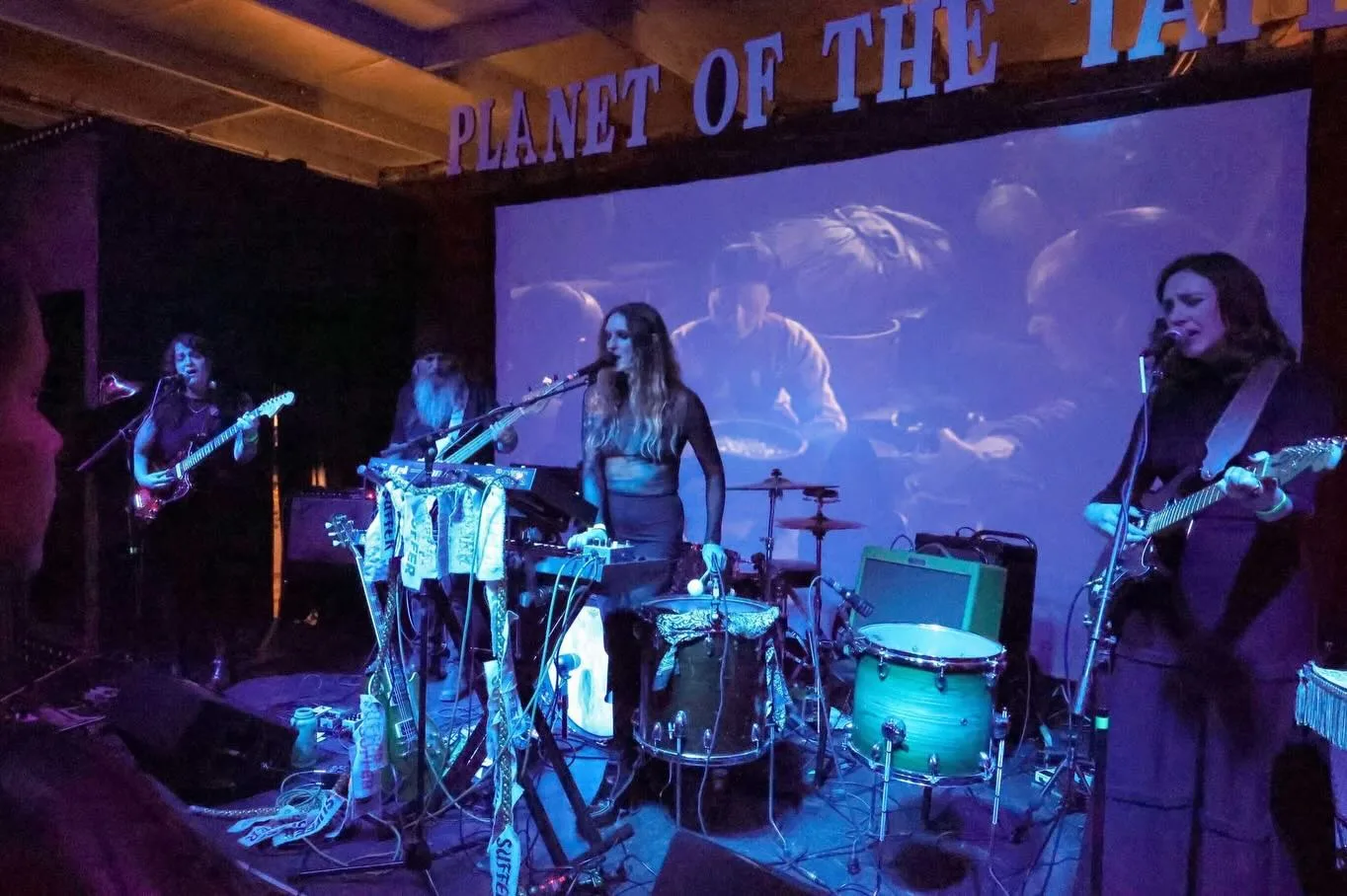 Band duchess on stage at Planet of the Tapes with SUFFER banners hanging from the keyboard stand.